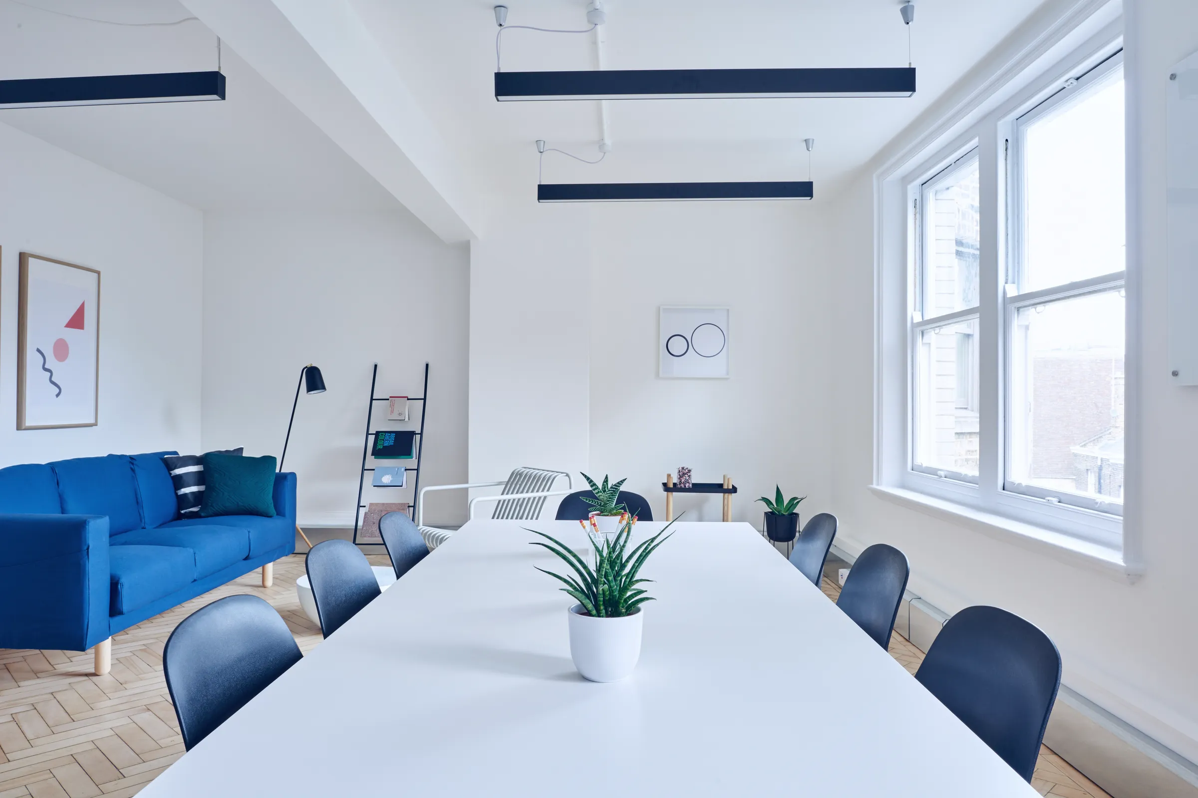 A meeting room with white walls and a herringbone floor.