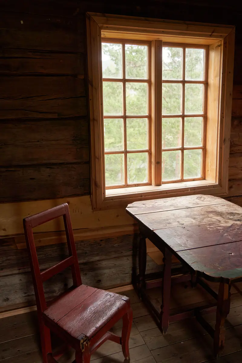 An old log wall, a small-paned window and a red chair
